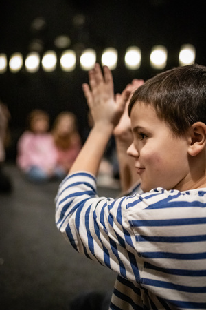 Filmowe ferie w kinie Marzenie - Na fotografii widzimy grupę dzieci na scenie przed ekranem, podczas animacji poprzedzających projekcje filmowe w ramach cyklu "Filmowe ferie".