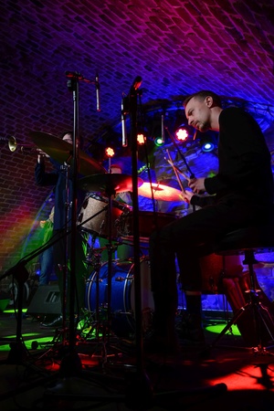 Koncert jazzowy: Tomasz Chyła Quintet - Zdjęcie sceny z koncertu Tomasz Chyła Quintet, pokazujące zaangażowanych muzyków. Tomasz Chyła gra na skrzypcach, w tle pozostali muzycy na różnych instrumentach. Scena jest dynamicznie oświetlona, co dodaje energii występowi.