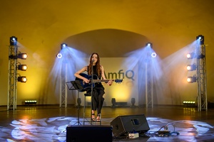 Koncert: "Ballady na głos i gitarę" - Łucja Kania - Na scenie śpiewająca i grająca na gitarze Łucja Kania