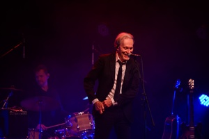 Koncert: John Porter - Helicopters'45 - Na scenie śpiewający John Porter, w tle grający na perkusji Robert Rasz