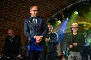 Benefis Bartka Szułakiewicza - Prezydent Tarnowa Jakub Kwaśny na scenie wręcza jubilatowi list gratulacyjny.