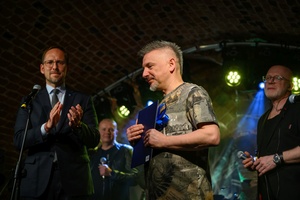 Benefis Bartka Szułakiewicza - Prezydent Tarnowa Jakub Kwaśny na scenie wręcza jubilatowi list gratulacyjny.