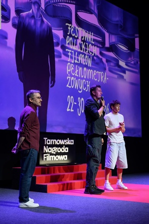 40. TNF: Dzień 6 (27.05.26) - Na scenie (od lewej) dyr. art. 40. TNF Kuba Armata, reżyser Maciej Sobieszczański, odtwórca głównej roli Filip Wiłkomirski zapraszający widzów na film "Brat"