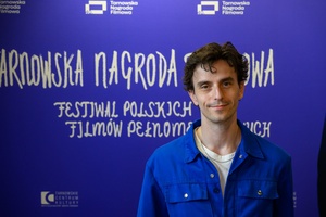 40. TNF: Dzień 6 (27.05.26) - W hallu Marzenia pozujący do zdjęcia na ściance festiwalowej współscenarzysta filmu "Nie ma duchów w mieszkaniu na Dobrej" - Kamil Marczak