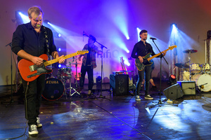 Koncert: Paragrafy i nuty - Wiesław Hudyma występujący na scenie amfiteatru w towarzystwie muzyków