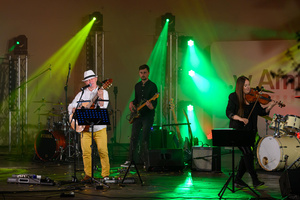 Koncert: Paragrafy i nuty - Wiesław Hudyma występujący na scenie amfiteatru w towarzystwie muzyków