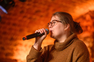 Koncert - Pracownia Piosenki "O jesieni..." - Wokalistka Pracowni Piosenki śpiewa do mikrofonu.